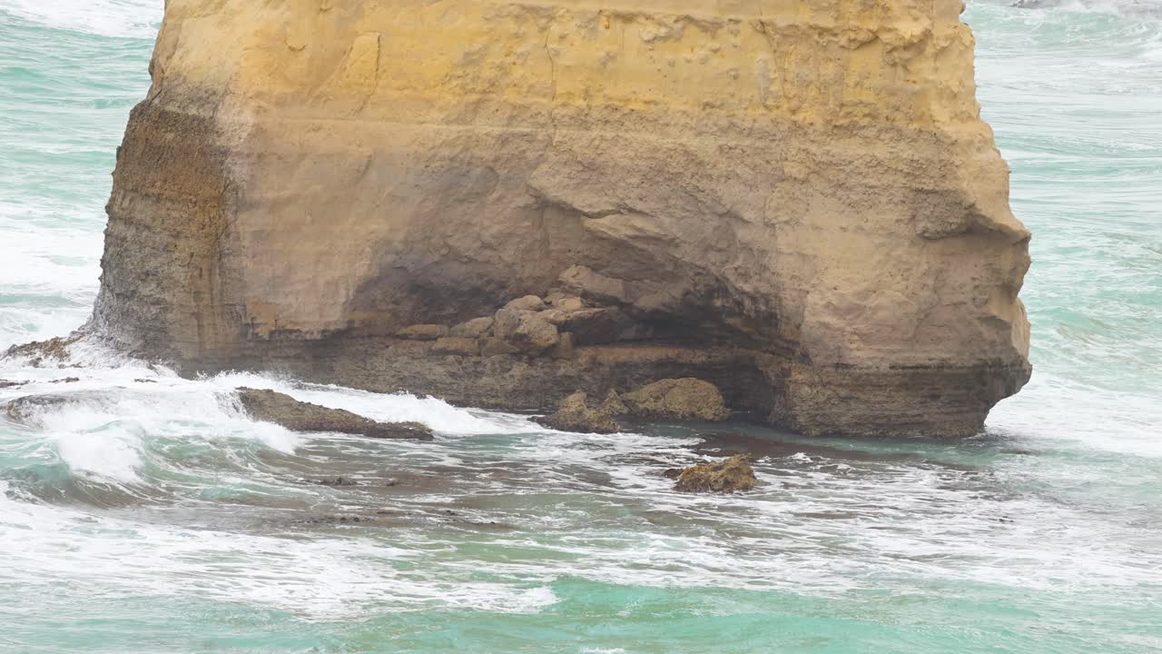 Dynamic ocean waves crash against the iconic limestone cliffs of the Twelve Apostles, captured in natural daylight at Port Campbell