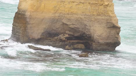 dynamic ocean waves crash against the iconic limestone cliffs of the twelve apostles, captured in natural daylight at port campbell