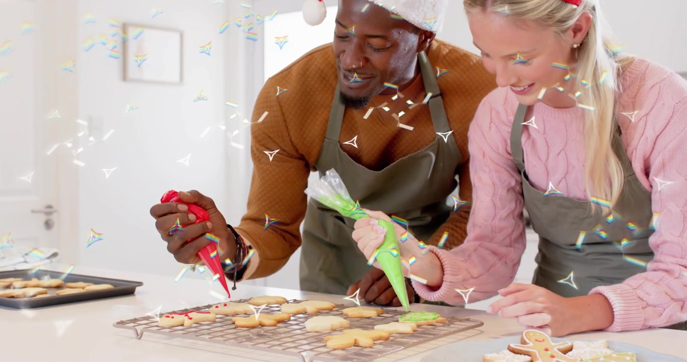 Baker duo spotting star cookies starting holiday decorating, outlining with red green icing bags