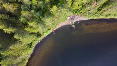 toma de drones de una isla en medio de un lago del norte con un kayak en la orilla