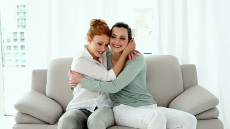 Two-beautiful-women-making-up-while-sitting-on-couch