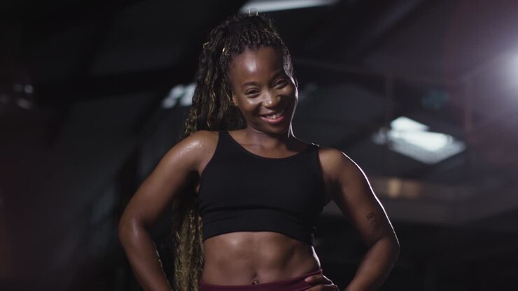 Studio-Porträt einer lächelnden Frau in Sportkleidung, die in einem Fitnessstudio steht 2