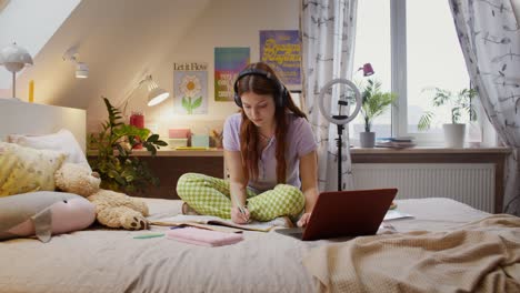 adolescente estudiando en línea en el dormitorio