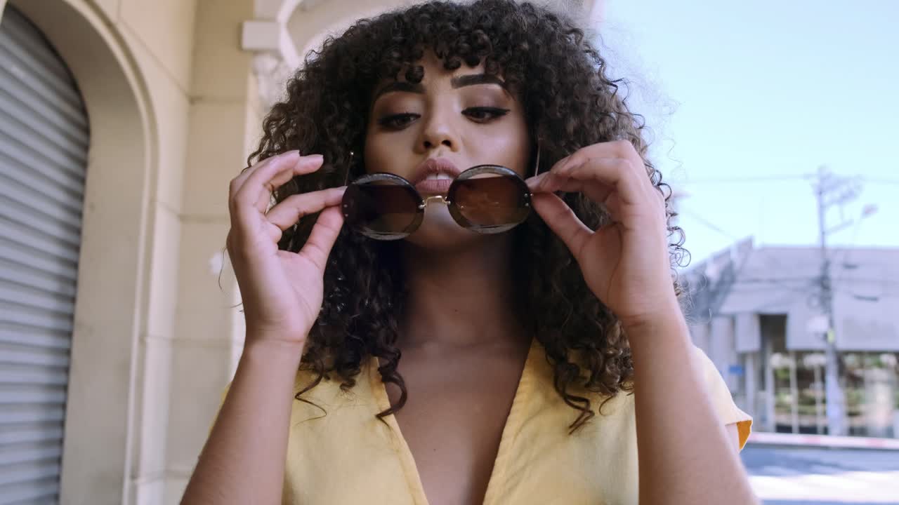 Une femme aux cheveux bouclés portant des lunettes de soleil