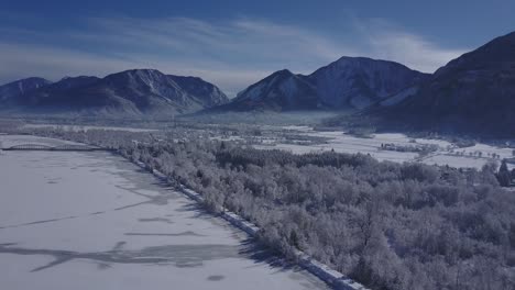 4k aerial video view of alpine snowy valley forest road and frozen river in peak of winter overflight - drone collection stock video