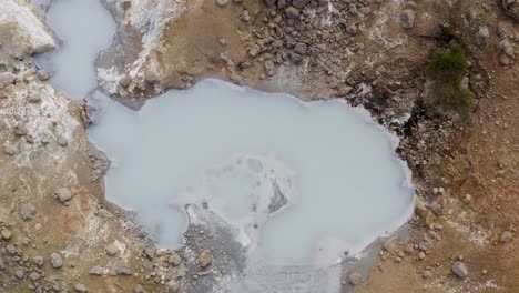 vuelo ascendente de arriba hacia abajo sobre lodo geotérmico con humos ascendentes en islandia
