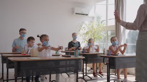 de leraar toont de kinderen de regels van persoonlijke hygiëne hoe ze hun handen moeten wassen hoe ze hun handen moeten behandelen met antisepticum. hoe ze een ontsmettingsmiddel moeten gebruiken. op school in beschermende maskers