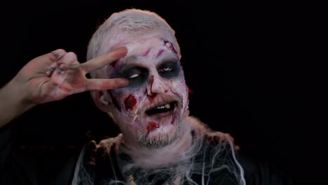 beängstigender mann mit halloween-zombie-make-up mit kopfhörern, musik hören, tanzen, feiern