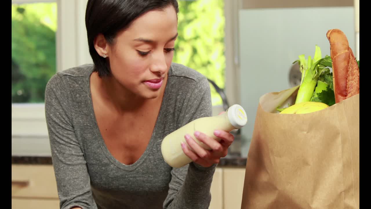 그녀가 방금 구입한 우유를 보는 여자