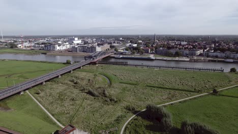 Auen-Mit-Stahlzugbrücke-Entlang-Des-Flusses-Ijssel-Mit-Turmstadt-Zutphen,-Niederlande-Auf-Der-Anderen-Seite-Der-Wasserstraße