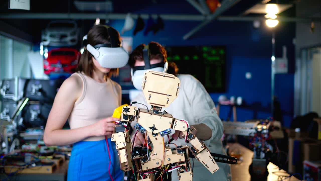 Two young engineers fixing a mechanical robot in the workshop, using VR virtual reality headsets