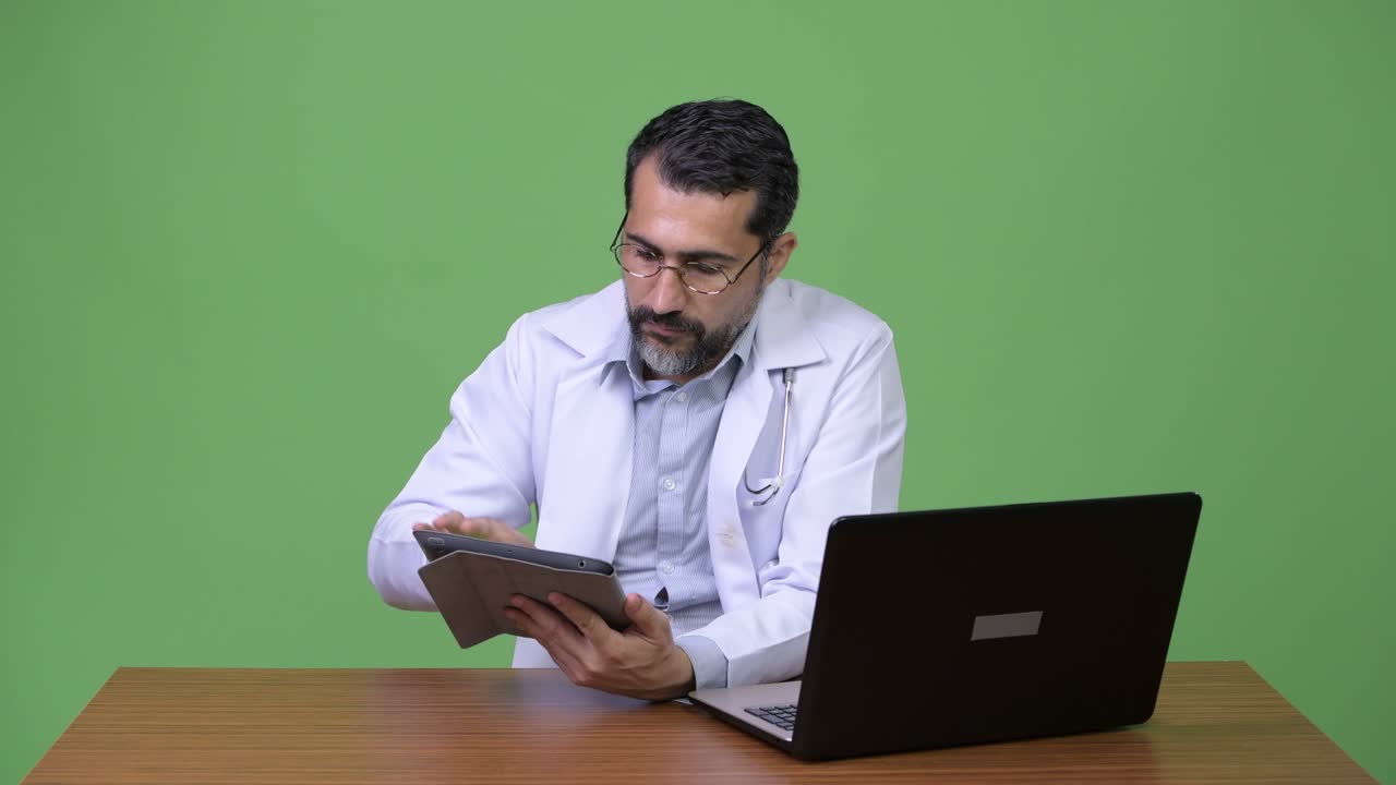 Handsome Persian bearded man doctor multi-tasking at work