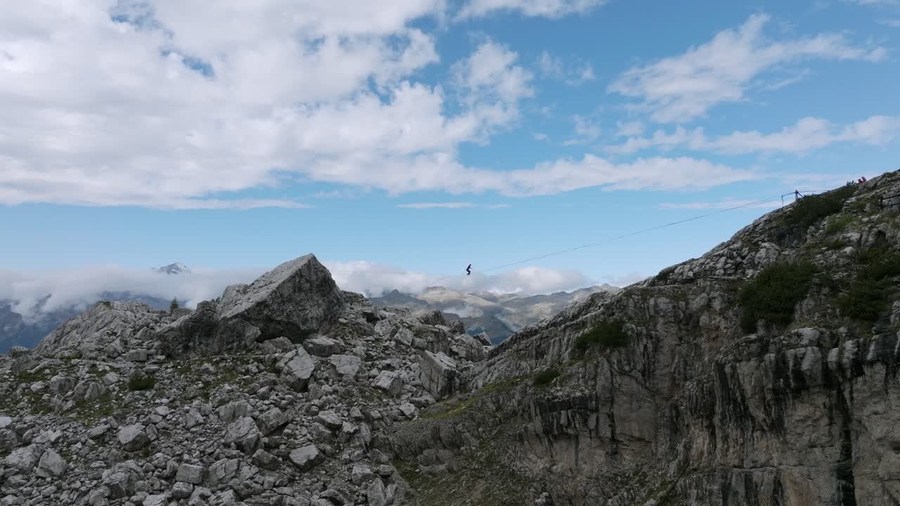 vuelo aéreo que muestra a una persona saltando en slackline sobre montañas en dolomitas