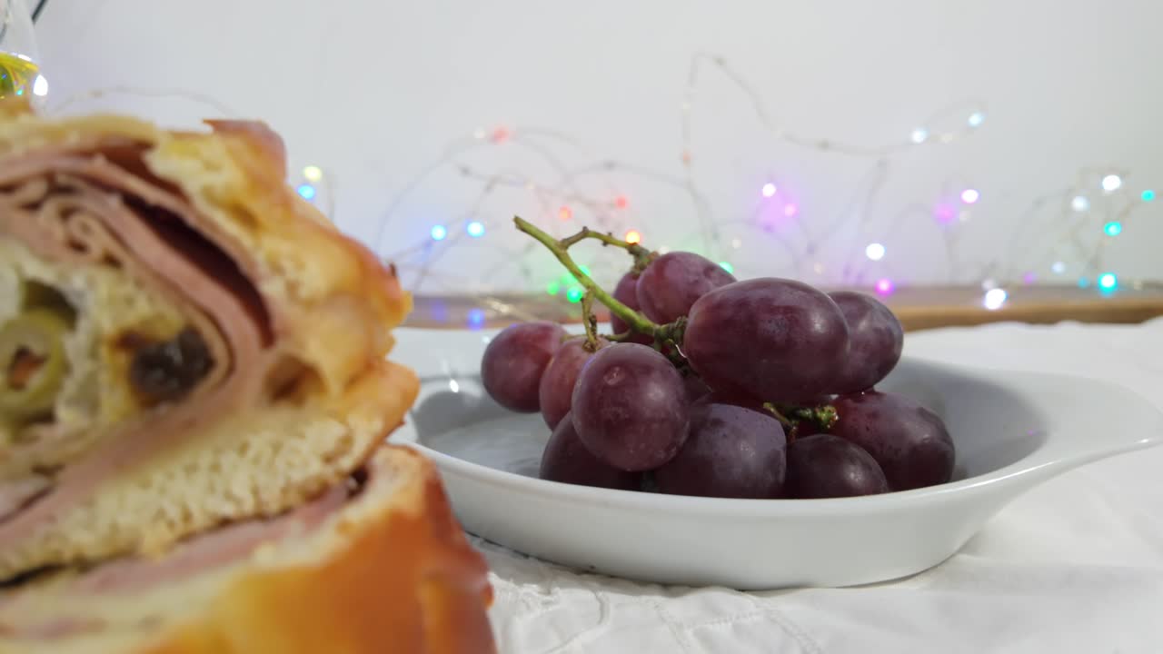 Close-up of fresh grapes on a white plate with colorful holiday lights in the background
