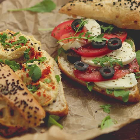 dos deliciosos sándwiches con hummus, tomate, queso mozarella, hierbas y aceitunas