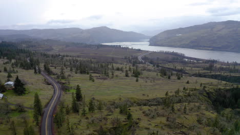 aerial view of a winding road through a river valley with mountains and farmland