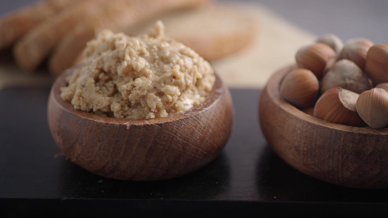 Close-up of Hazelnut Butter and Whole Hazelnuts in Wooden Bowls