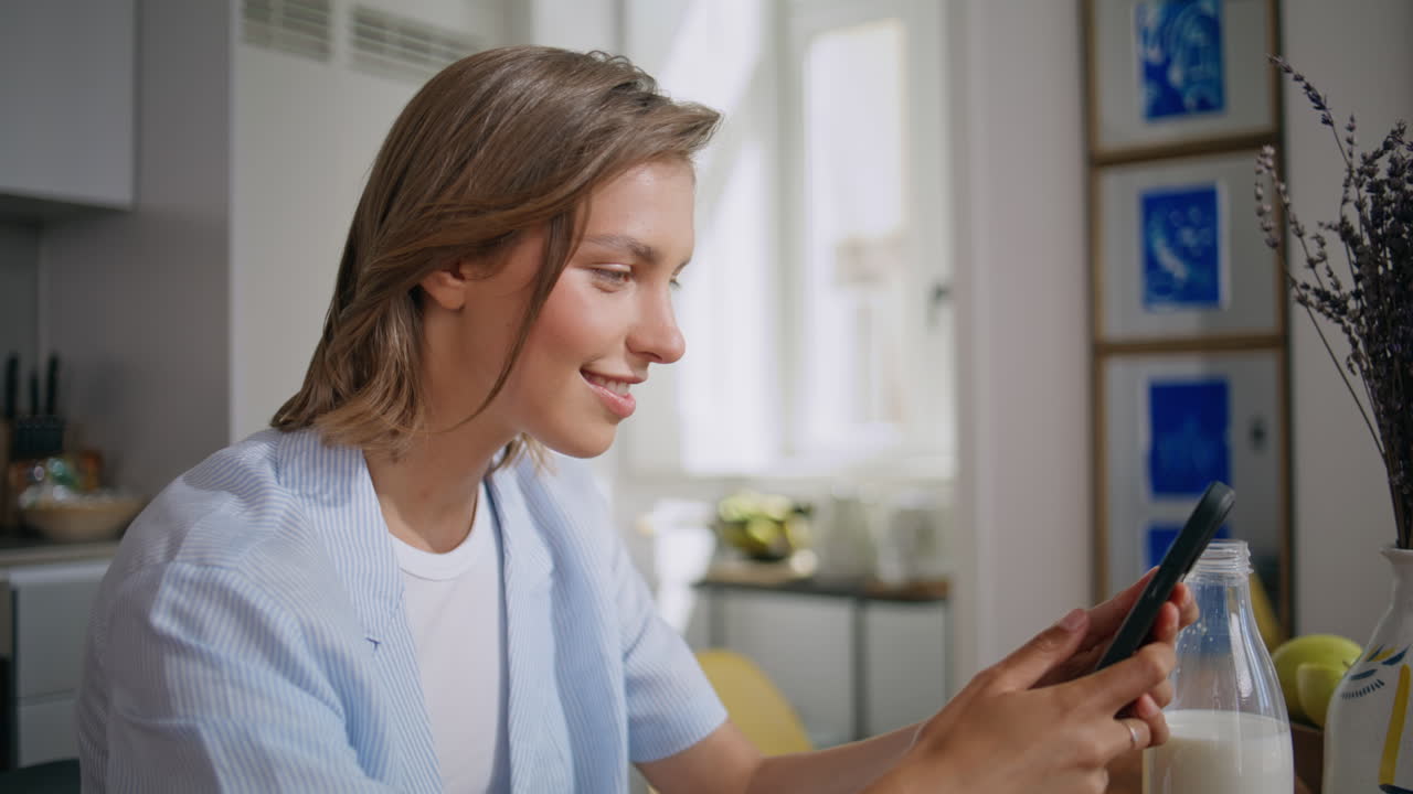 Home girl messaging cellphone in sunny kitchen closeup. Joyful woman text online