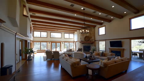 luxurious and spacious living room with high ceilings, exposed beams, and a large stone fireplace