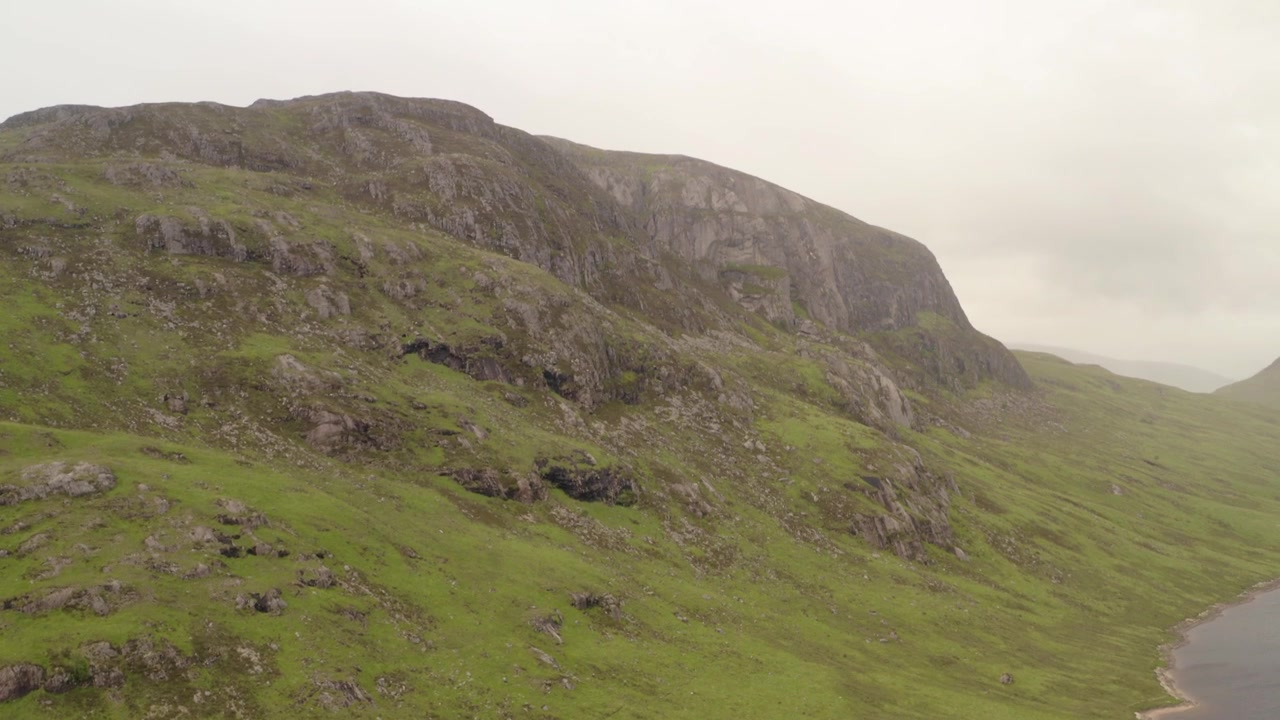 Il drone rivela una scogliera frastagliata che si erge accanto a un loch delle Highlands, Scozia