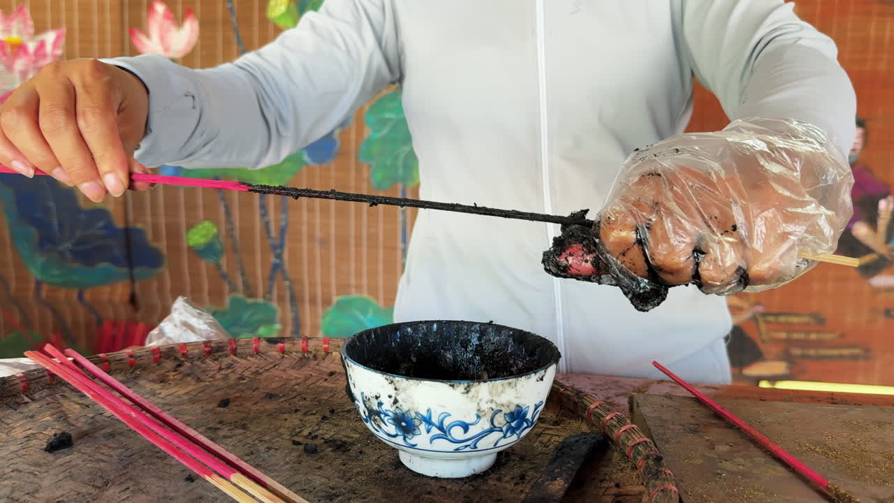 Hand crafting incense sticks by dipping them in black paste at Quảng Phú Cầu Village