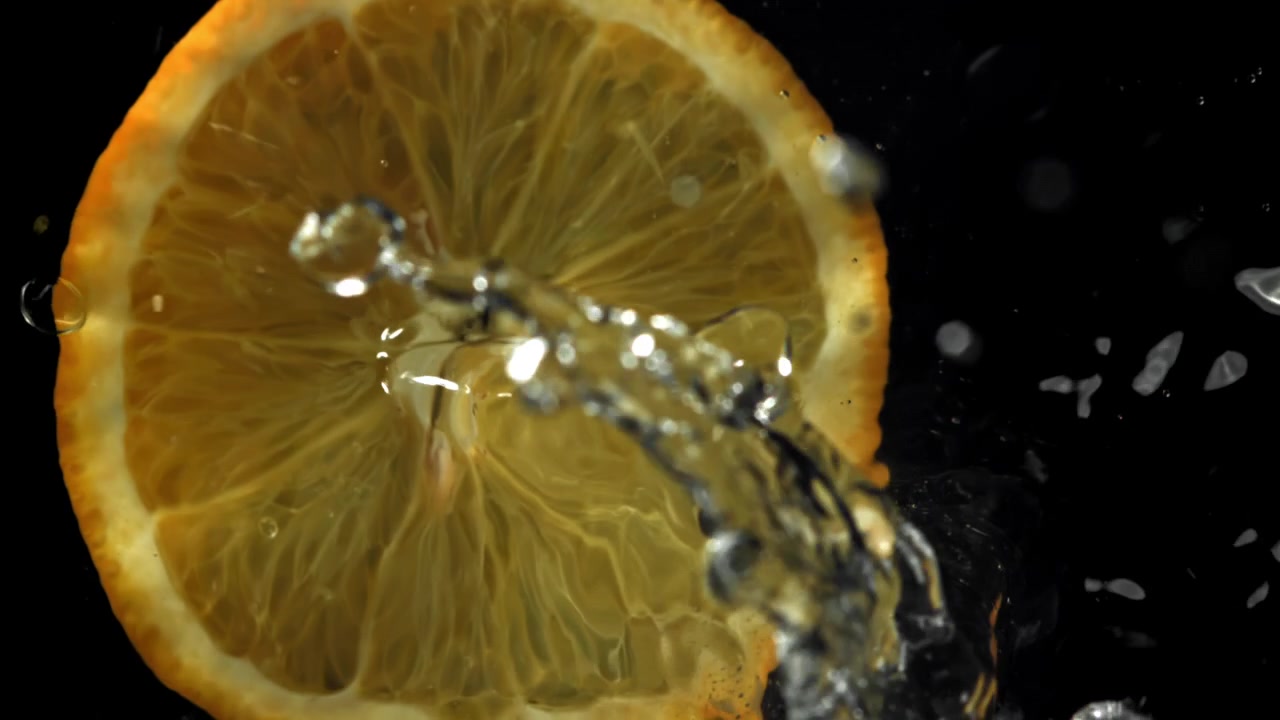 Fetta d'arancia vivace con schizzi d'acqua su sfondo nero