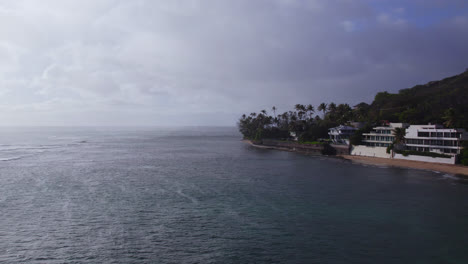 Toma-Aérea-A-Lo-Largo-De-La-Costa-De-Honolulu-En-Oahu-Hawaii-Con-El-Océano-Pacífico-A-La-Izquierda-Y-El-Cielo-Nublado-Y-El-Océano-Pacífico.