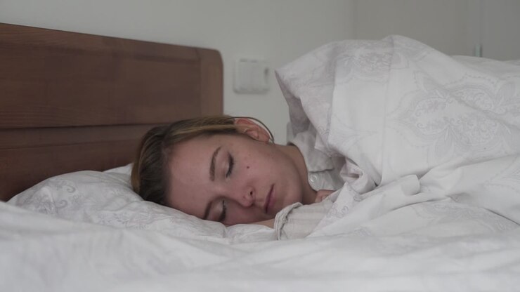 Chica caucásica morena durmiendo en la cama de lado
