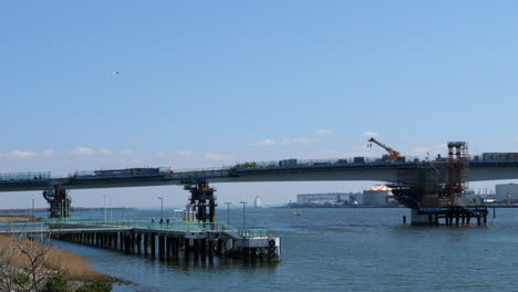 Avión-Despegando-Sobre-La-Construcción-Del-Puente,-Aeropuerto-De-Tokyo-Haneda