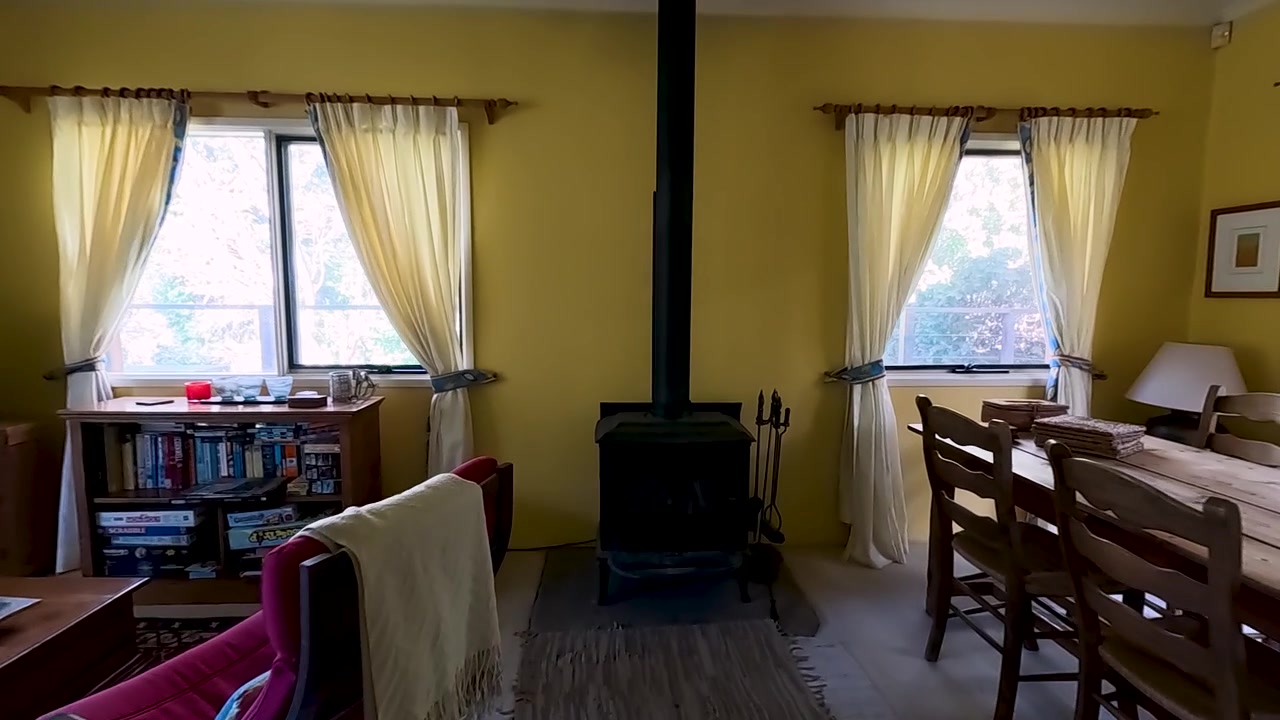 La telecamera si muove attraverso un corridoio in un accogliente soggiorno con una stufa a legna.