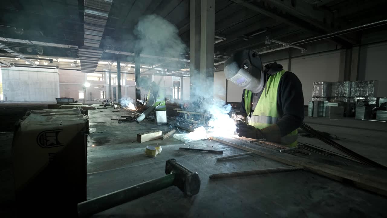 전문 용접자는 안전 장비를 착용하여 공장에서 일하고 있습니다.