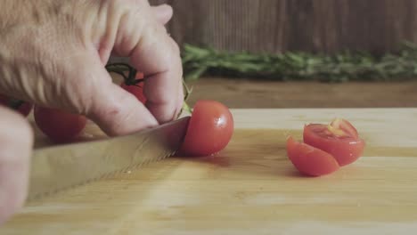 Ältere-Hausfrau-Schneidet-Kirschtomaten-Mit-Scharfem-Messer-Auf-Einem-Küchentisch-Aus-Holz