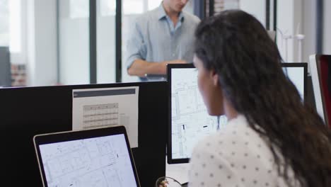 Portrait-of-woman-smiling-while-sitting-on-her-desk-at-office