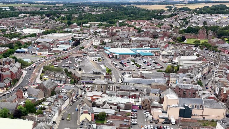 Un drone si muove lentamente sopra il paesaggio urbano di Dundee, mostrando edifici residenziali, strade e panorama urbano alla luce del giorno