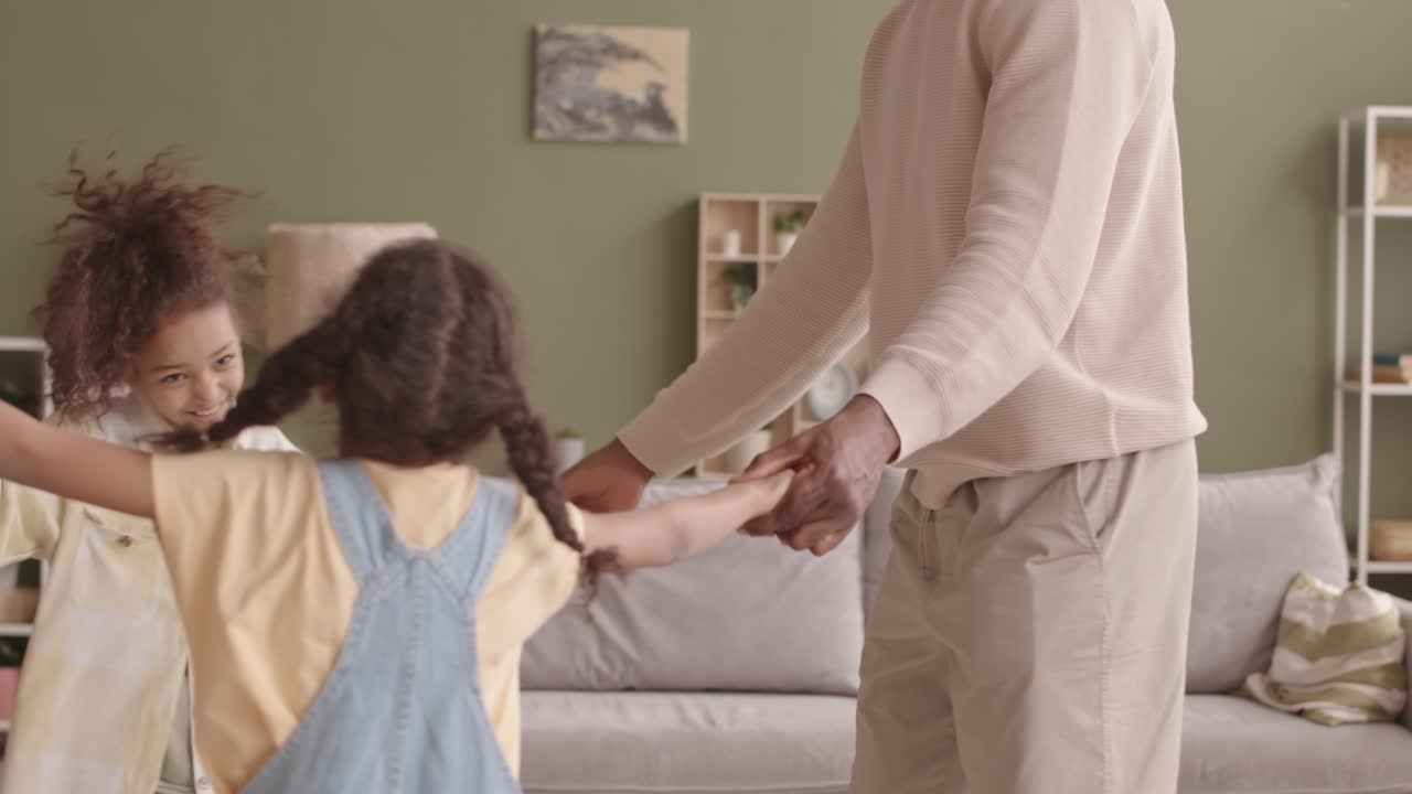 아프리카계 미국인 가족 4명이 거실에서 서클 댄스를 하고 있습니다.