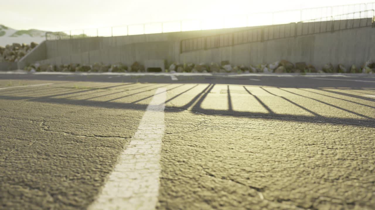 Shadows stretch across an empty parking lot at sunset in a tranquil setting