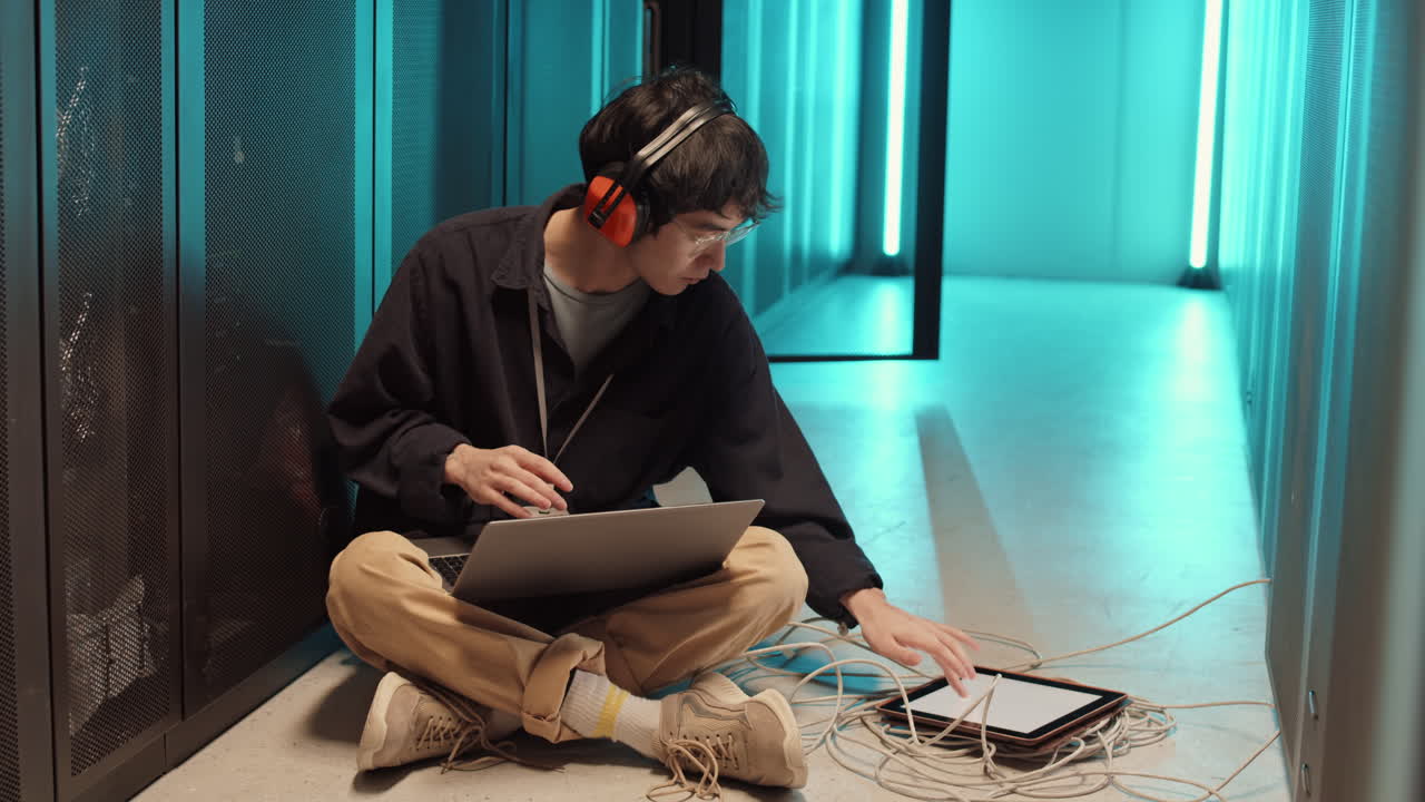Asian IT Specialist Coding on Laptop in Server Room