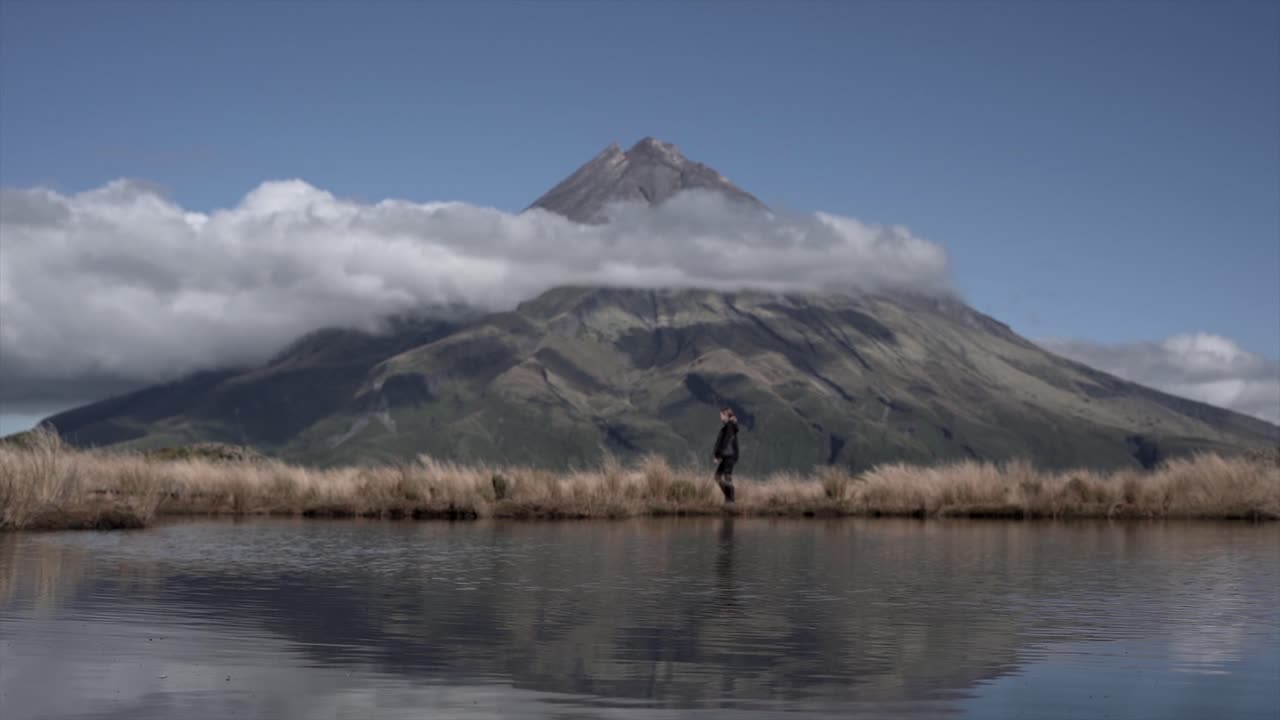 Person Walking by Lake with Mountain View