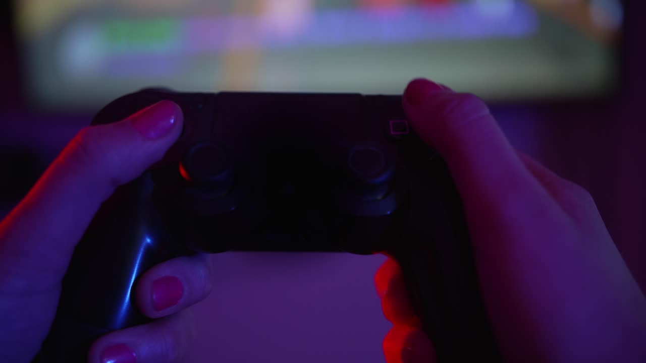 Close-up of Hands Playing Video Game with Controller in Neon Light