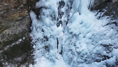 Drone-shot-of-frozen-waterfall-between-rocks