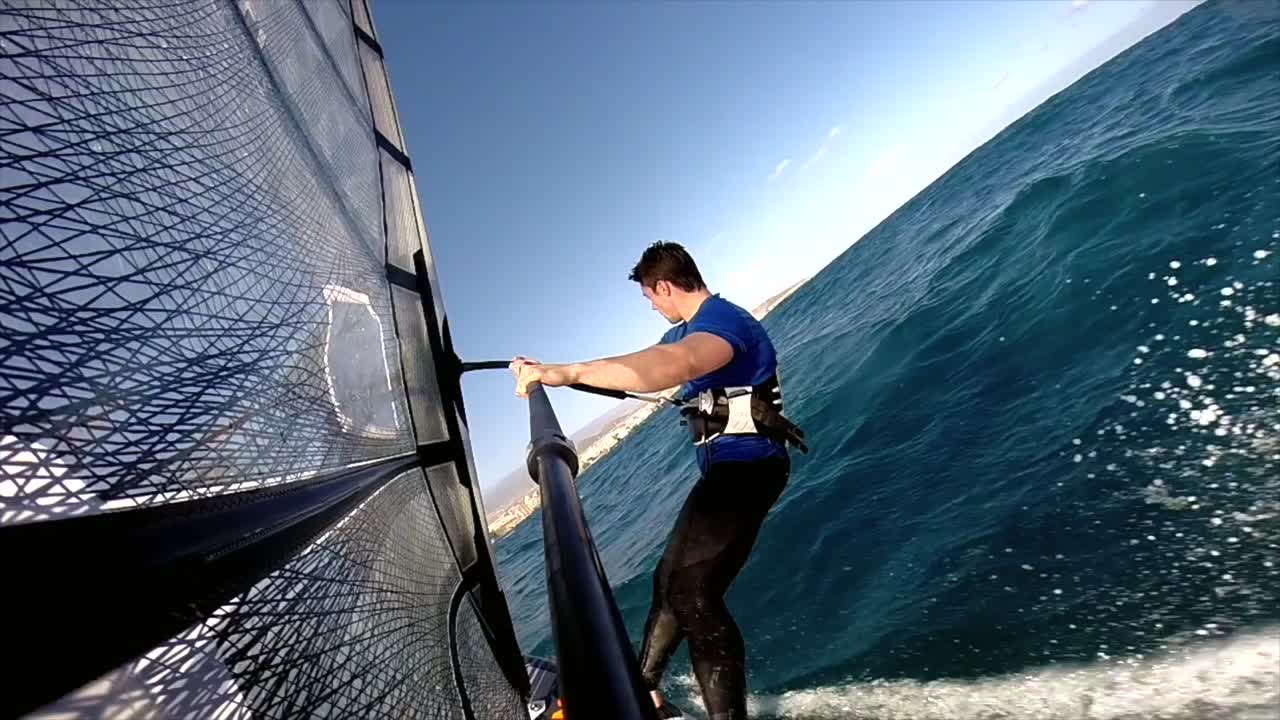 una vista trasera de un windsurfista activo planeando a través del océano