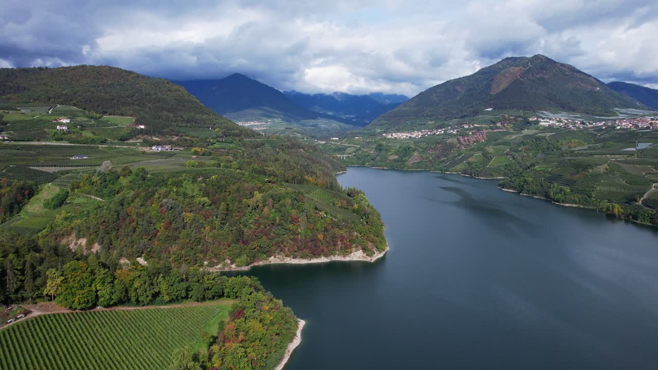 Drone che vola lateralmente sopra il Lago di Santa Giustina rivelando la valle di Cagnò e Dres
