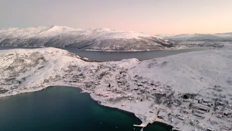 aerial establishing shot of the small village ersfjordvegen surrounded by snow