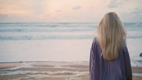 ocean girl looking camera at beautiful sky closeup. woman walking evening shore