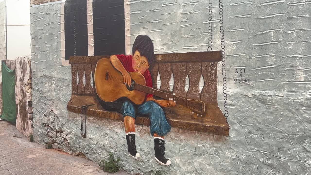 Wall mural depicting a child playing guitar in the old town of Chersonissos, Crete, Greece