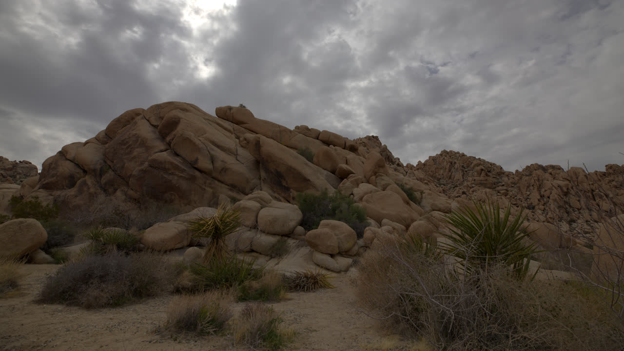Timelapse af skyet himmel i Joshua Tree Nationalpark bag et stort bjerg af kampesten og klipper i Californien