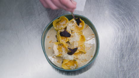 cook decorates ravioli with flowers using tongs