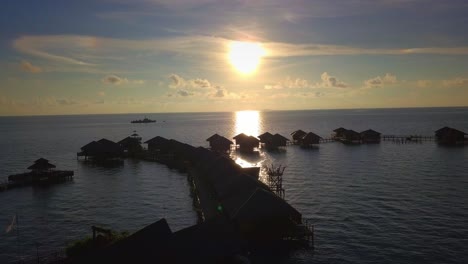 Aerial-flight-towards-stunning-sunset-over-floating-huts-in-Mabul,-Malaysia