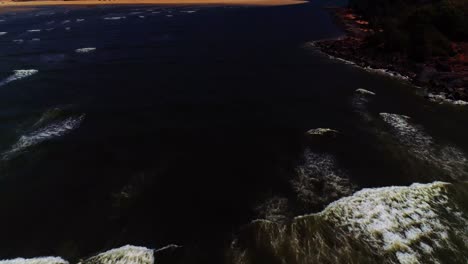 Drohnenaufnahmen,-Die-Den-Wellen-Folgen,-Die-Auf-Einen-Felsigen-Strand-Schlagen,-Aufgenommen-In-Südgoa