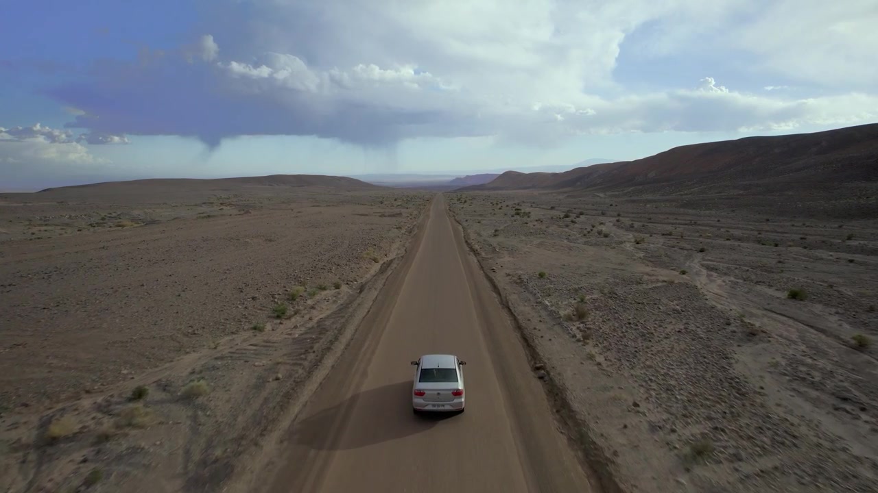 Ripresa aerea bassa di un'auto che guida su una strada nel deserto tra i Geyser El Tatio e San Pedro de Atacama, Cile.